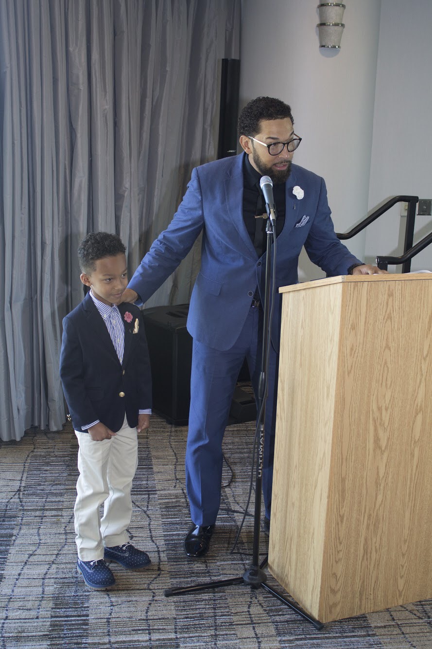 Dr. Martinez speaking at a lectern with his son beside him